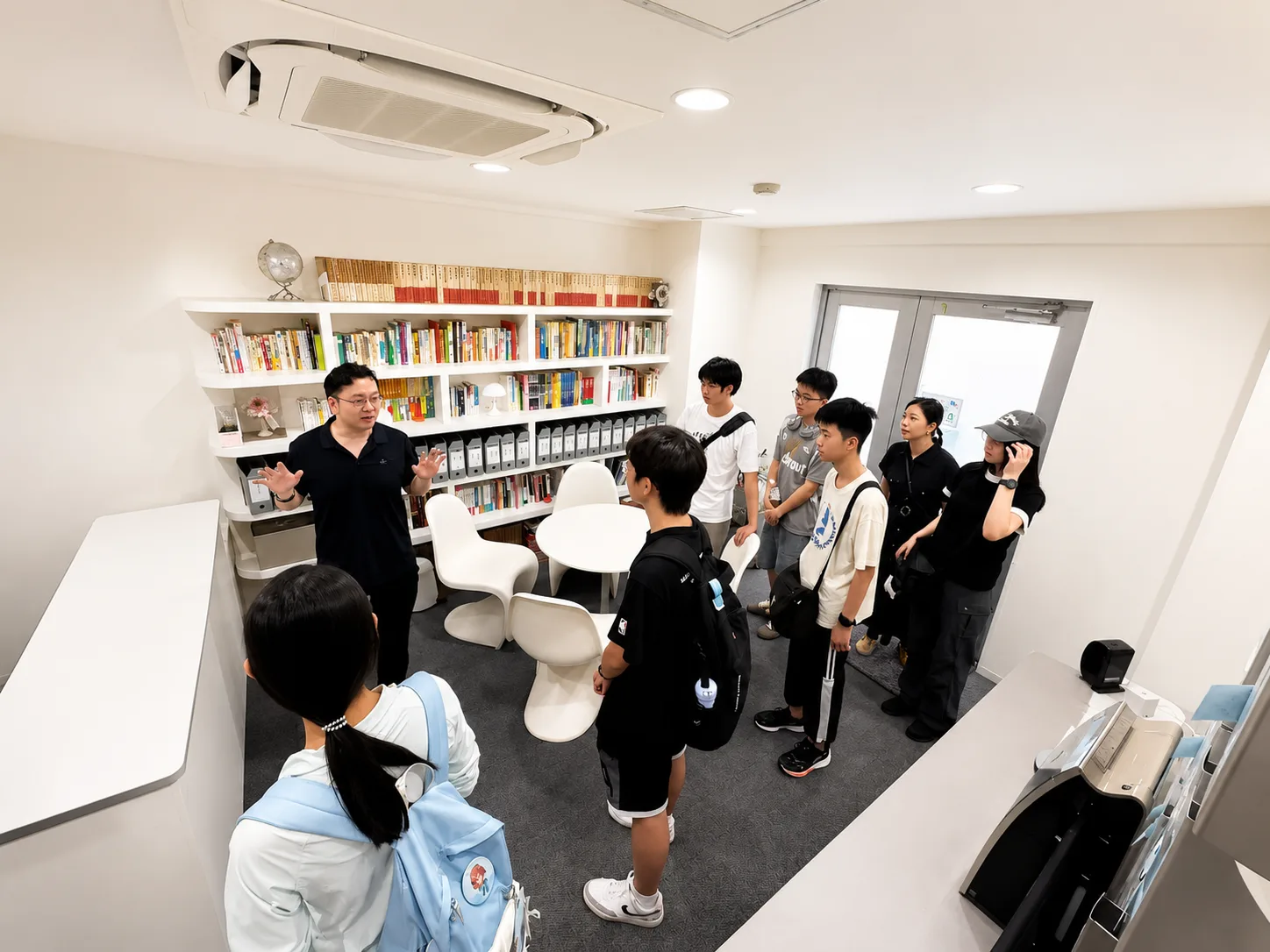 クリックで拡大 アドバイザーが書棚の前で学生に進学相談を行う様子